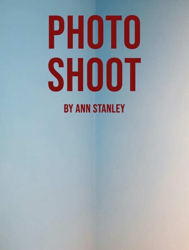 A bare pale blue wall, with the title Photo Shoot by Ann Stanley